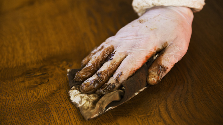 hand wiping dark wood varnish with cloth