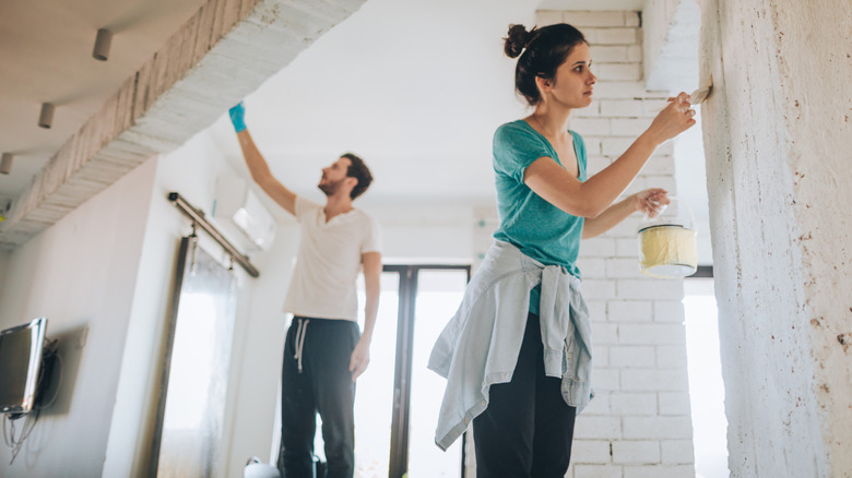 couple whitewashing wood paneling