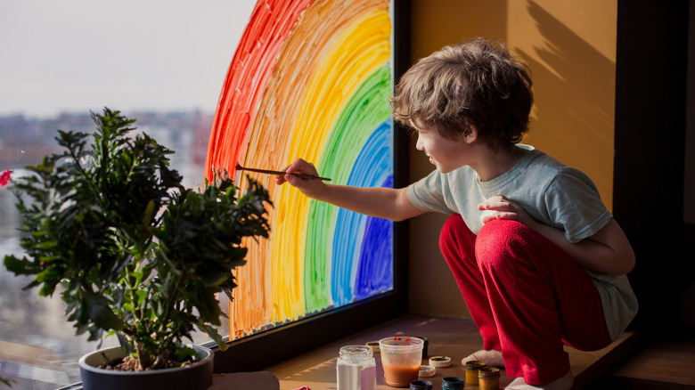 childing painting rainbow on window