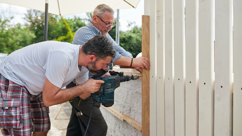 Two people installing a fence