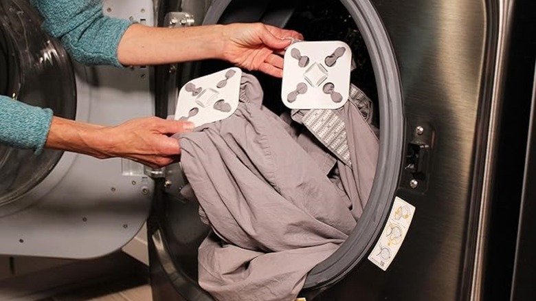 Person putting sheets in the dryer with Wad-Frees on them