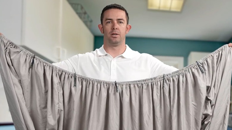 A man using the Laundry Buddy to close a fitted sheet