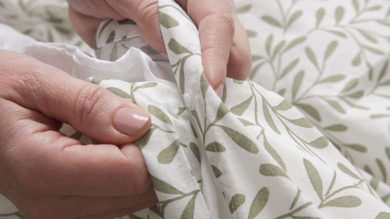 A person buttoning a duvet cover