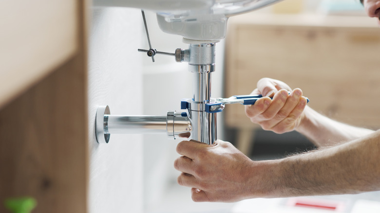 A person fixing a broken pipe