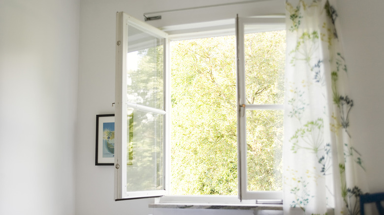 Open casement window with sheer floral curtain