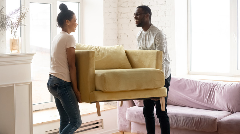 Two people lifting a living room chair