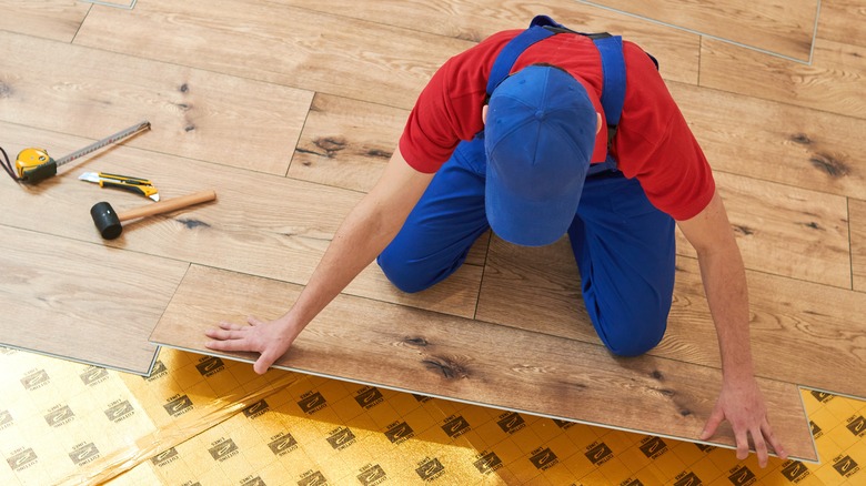 Man laying wide vinyl planks