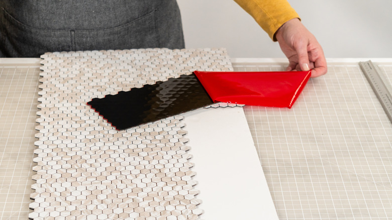 Person peeling the adhesive off a peel-and-stick tile