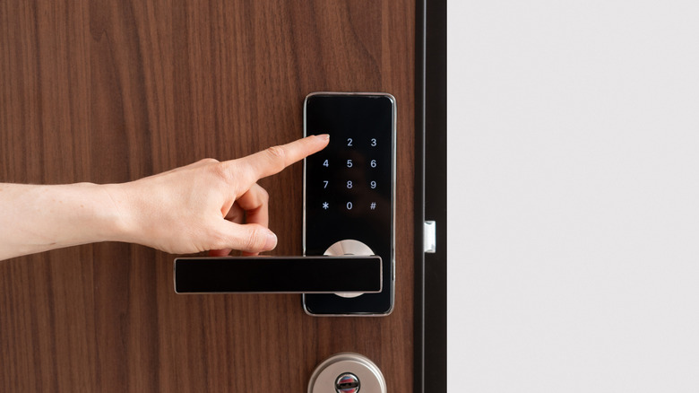 Hand pressing touchscreen keypad on a smart lock