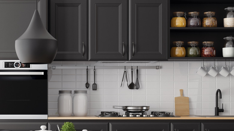 A kitchen with black cabinets and a white backsplash