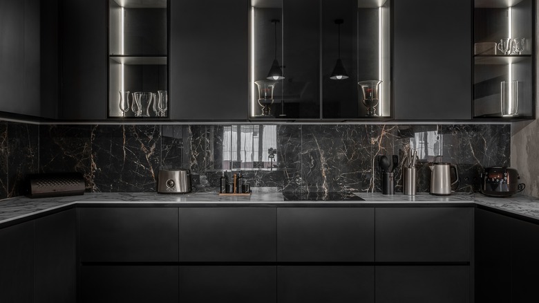 A kitchen with black cabinets and a black marble backsplash