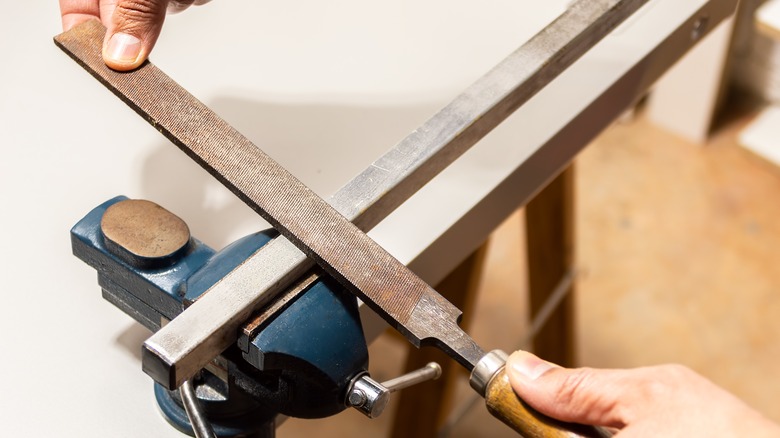 Person working with a blunt metal file.