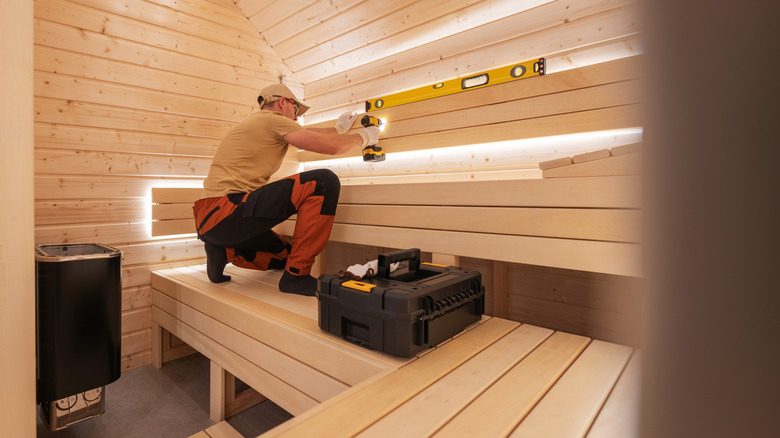 A carpenter uses a level while building a sauna