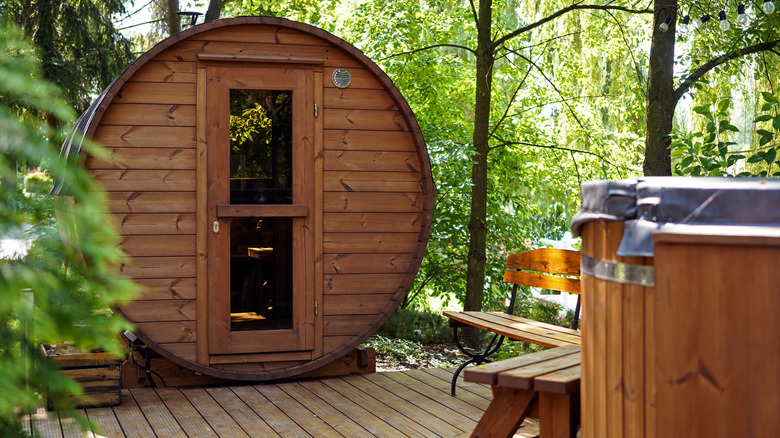 An outdoor sauna is pictured in a wooded yard