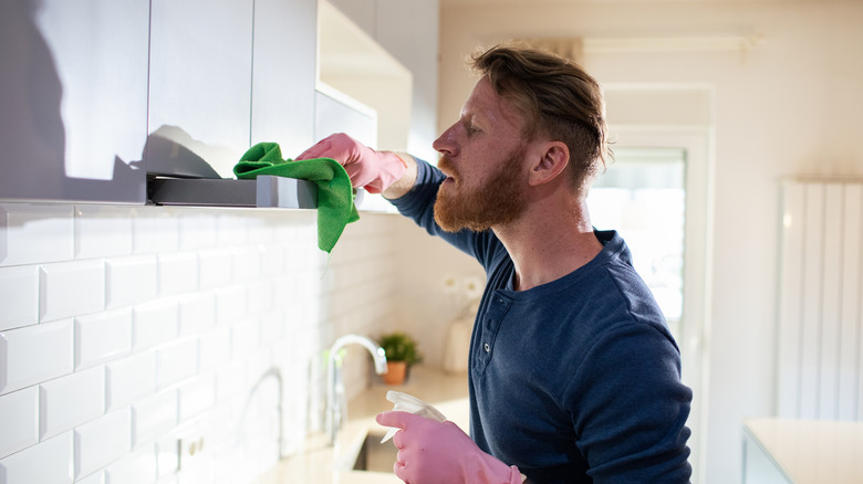 A man cleaning his kitchen with a green microfiber cloth