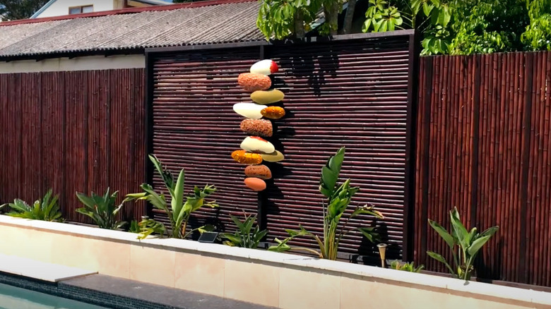 A stained and sealed bamboo privacy fence with an art feature and plants