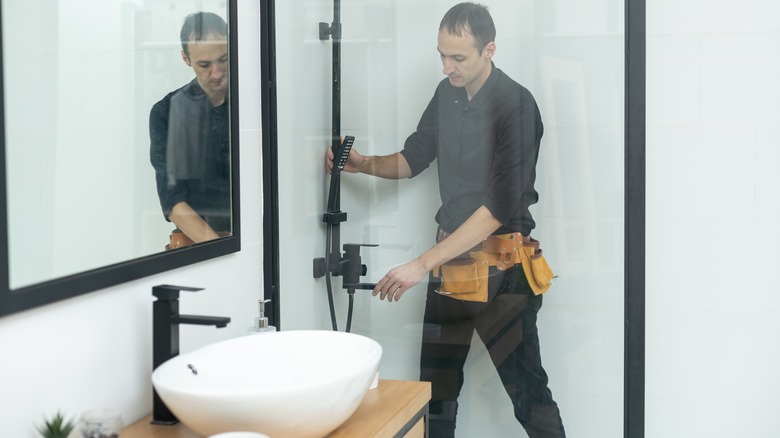 Man installing showerhead in shower