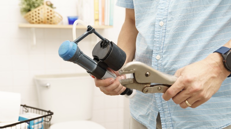 man holding toilet fill valve