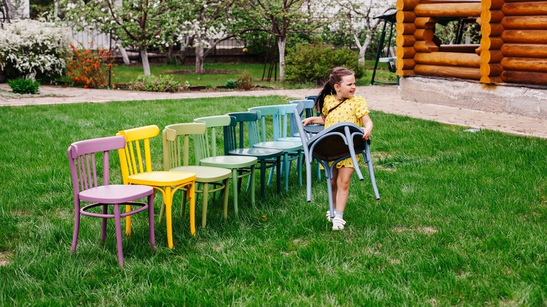 Girl carrying chair in grass