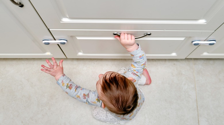 baby touching cabinet with locks