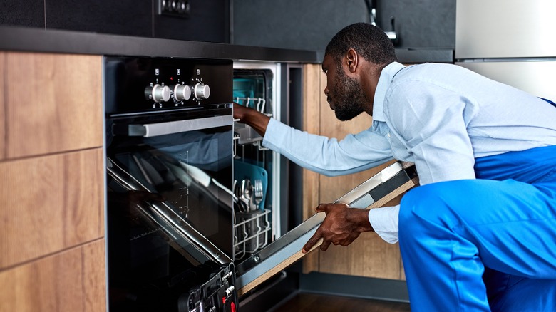 man opening dishwasher in kitchen