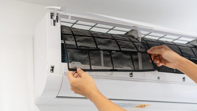 Woman cleaning air conditioner filter
