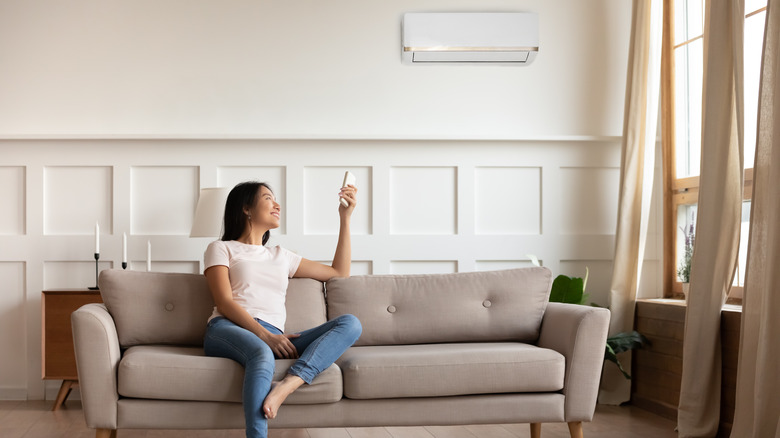 Woman turning on air conditioner 
