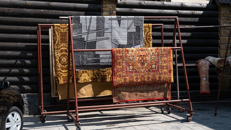 different carpets hanging on rack outdoors