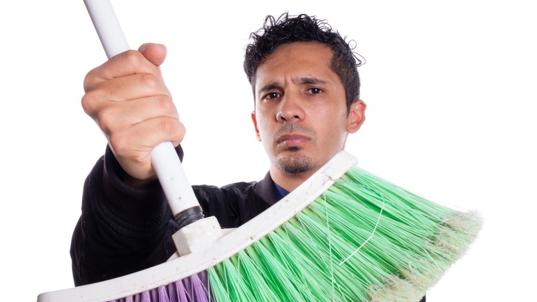 man showing broom on white background