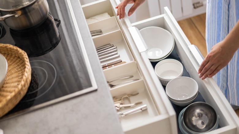 Woman opening clean kitchen drawer