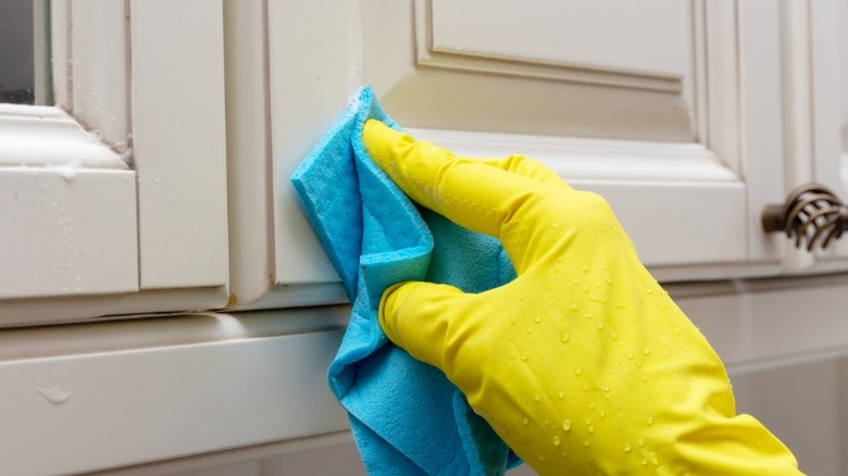 Yellow gloved hand cleaning cabinet