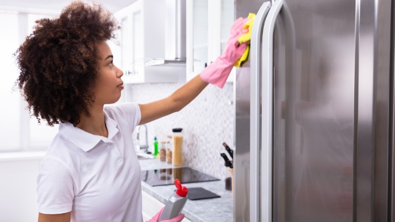 Woman cleaning outside of refrigerator