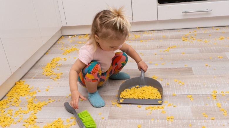 Toddler girl on floor with dustpan