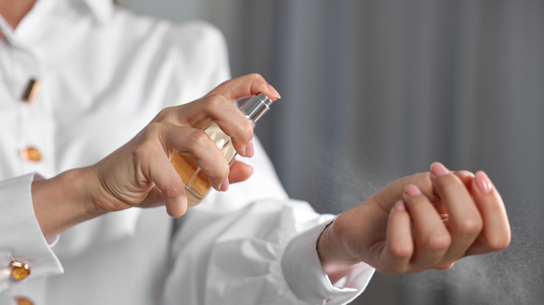 Woman spraying perfume onto wrist