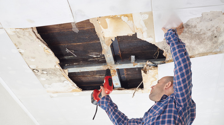 man repairing damaged ceiling