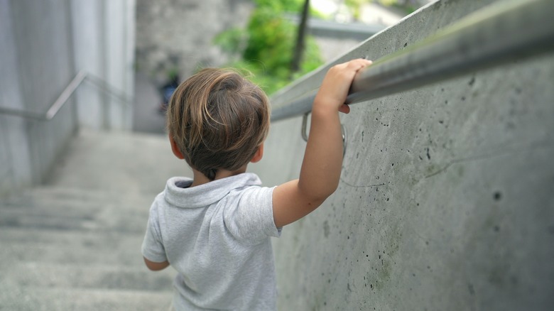 child using handrail on stairs