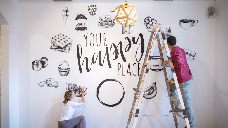 A man and a woman painting a mural