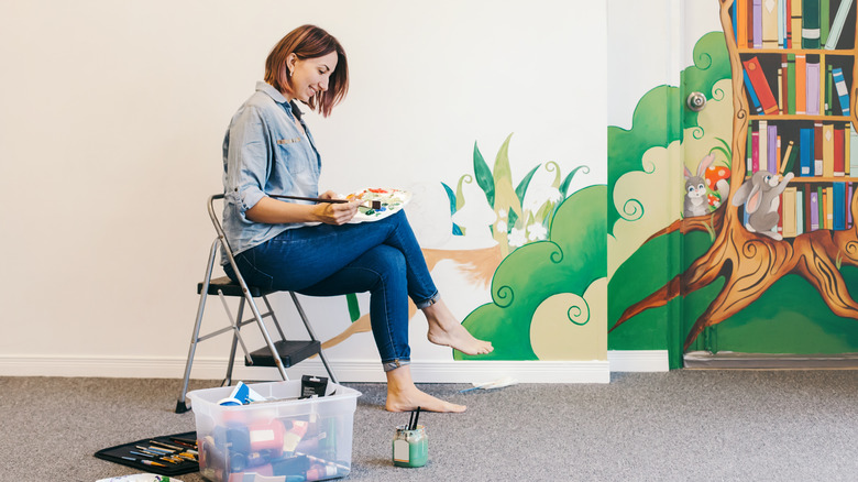 A lady painting a wall mural 