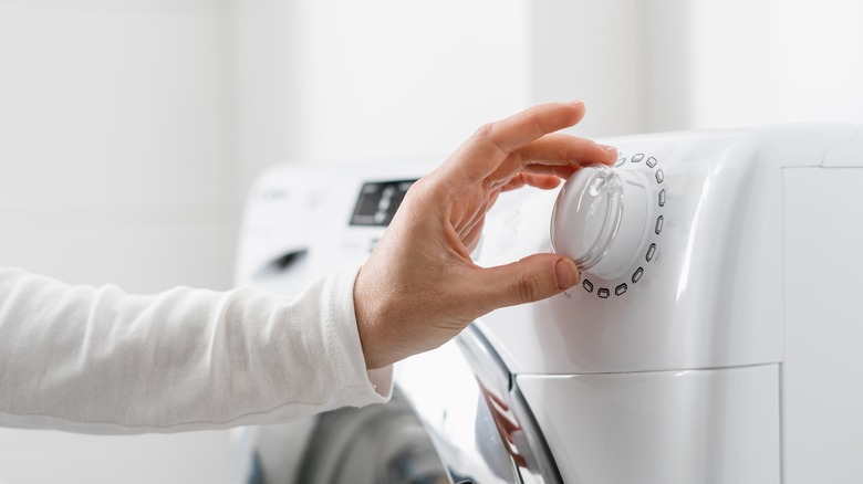 hand on washing machine dial 