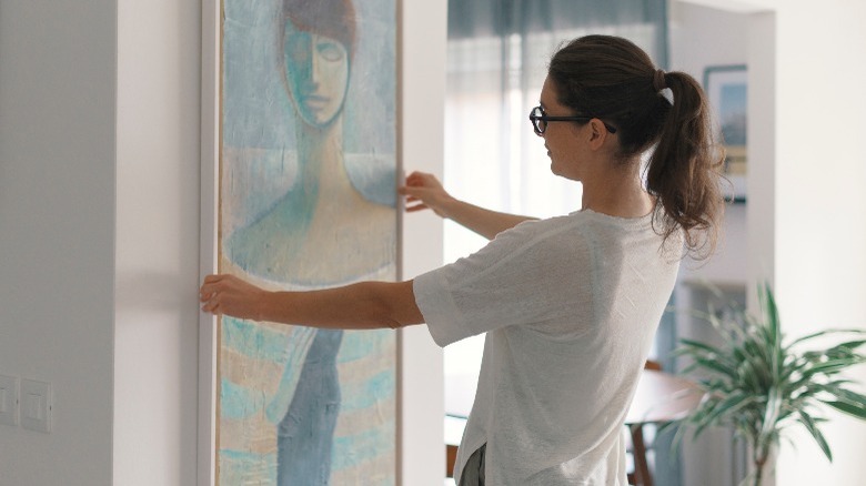 Woman hanging artwork in house 