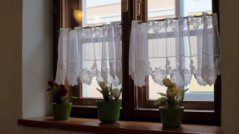 White cafe curtains with flower patterns hanging in two windows