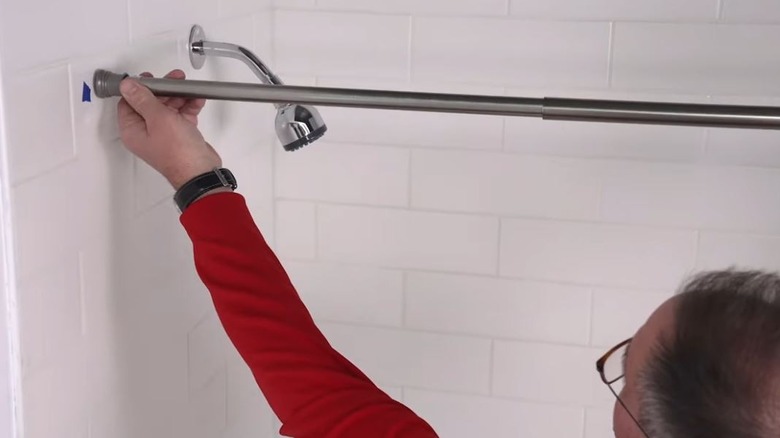 Man tightening tension rod in shower