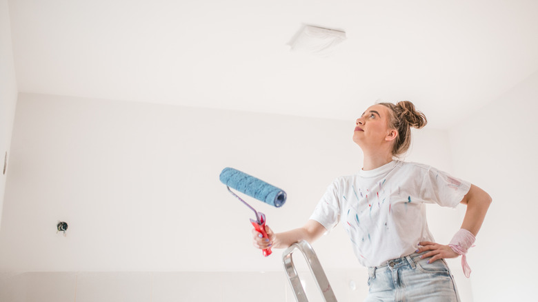 young woman preparing to paint ceiling