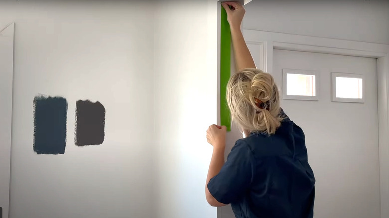 blonde woman applying painter's tape to door frame