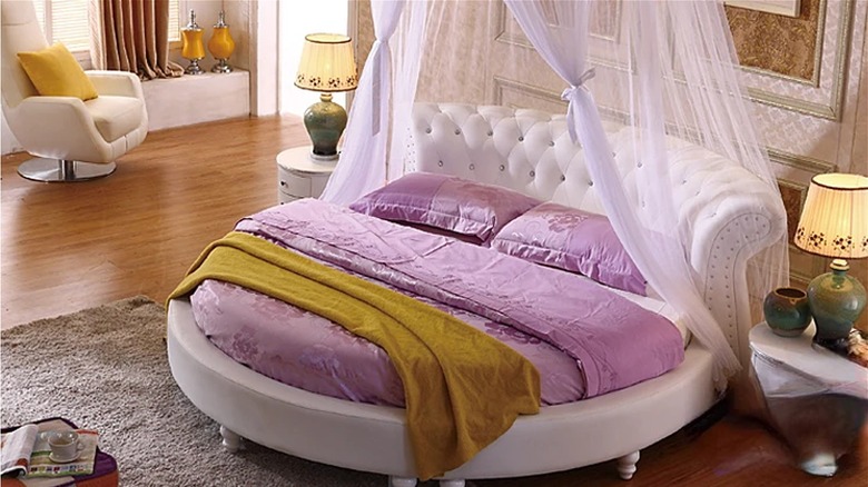 Round bed with drapes and tufted headboard