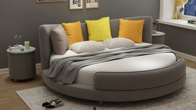 Gray, modern, round bed with yellow pillows