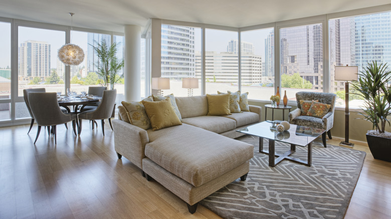 A gray sectional sofa in a living room with a dining area to the side