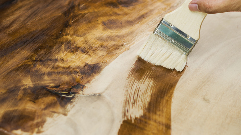 A person is staining wood with a brush.