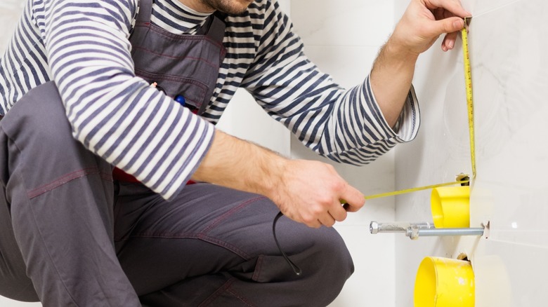 Person measuring bathroom wall