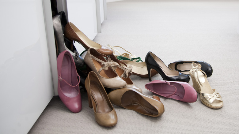 Disorganized pile of shoes falling out of closet